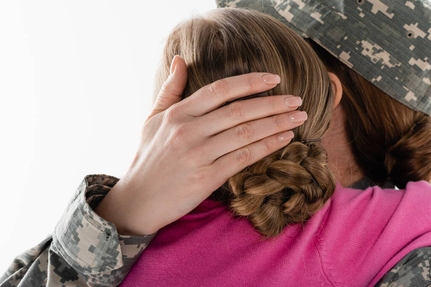 Мать в военной форме обнимает ребенка изолированного на белом  - Фото, изображение