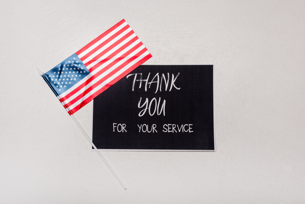 Widok z góry amerykańskiej flagi w pobliżu karty z podziękowaniami za napisy usługi na szarym tle - Zdjęcie, obraz