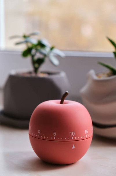 Moderne appel vormige timer naast ramen met warme zonsopgang verlichting, bel timer - kleine helper op de keuken - Foto, afbeelding