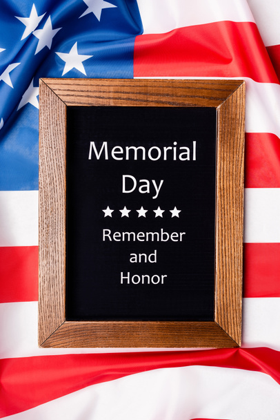 Top view of memorial day remember and honor lettering on chalkboard on american flag  - Photo, Image