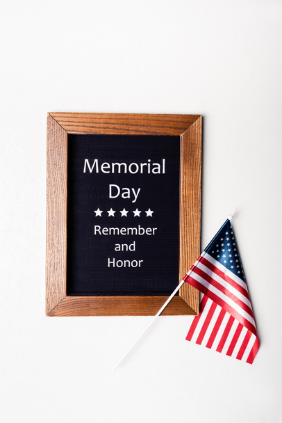 Draufsicht auf amerikanische Flagge und Tafel mit Gedenktag erinnern und Ehren-Schriftzug auf weißem Hintergrund  - Foto, Bild