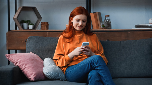 Adolescente positivo usando smartphone en la sala de estar  - Foto, Imagen