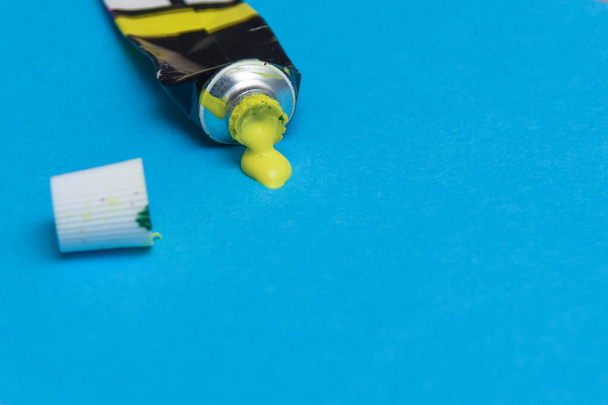 Tubo de derramamento de tinta acrílica amarela sobre fundo de papel de arte - Foto, Imagem