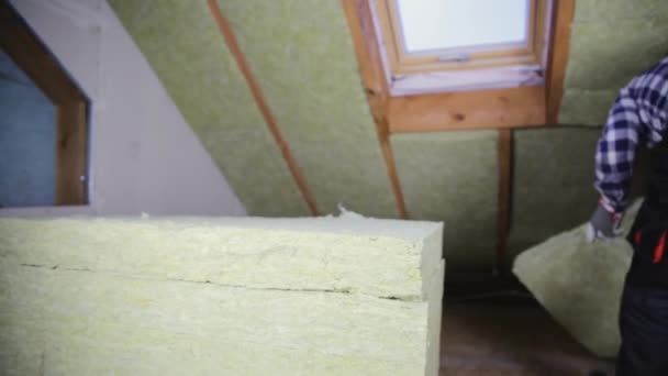 Uomo che installa strato di isolamento termico del tetto - utilizzando pannelli di lana minerale. Mansarda concetto di ristrutturazione e isolamento - Filmati, video