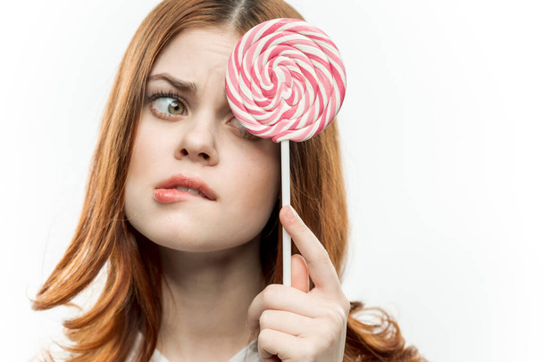 atractiva mujer cubriendo la cara con caramelo caramelo emoción de cerca - Foto, imagen