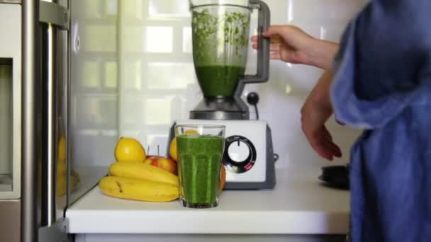 Mujer que mezcla espinacas, plátanos, limón y manzanas para hacer un batido verde saludable. Concepto de vida saludable - Imágenes, Vídeo
