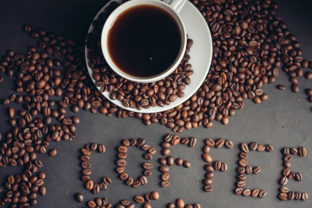 granos de café aromáticos y una bebida en una taza de fondo gris vista superior - Foto, imagen