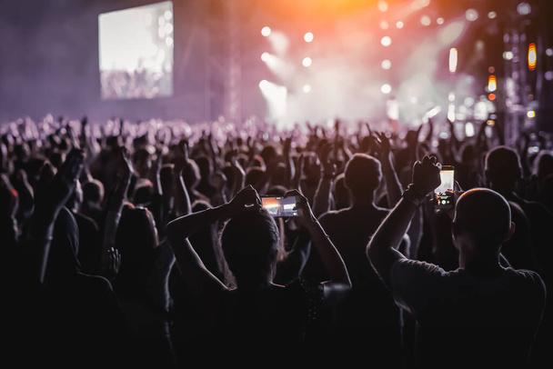 Persone con le mani alzate, silhouette di folla concerto di fronte a luci di scena luminose - Foto, immagini