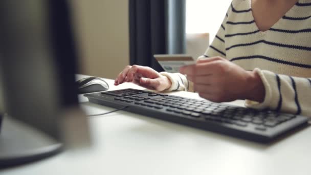 Młoda kobieta trzyma kartę kredytową i używa komputera. Koncepcja zakupów online. Transakcja płatnicza przy użyciu karty kredytowej - Materiał filmowy, wideo