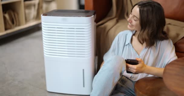 Femme avec purificateur d'air ou climatiseur à la maison - Séquence, vidéo