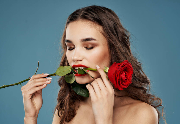 Woman with a rose in her teeth evening makeup blue background model - Photo, Image