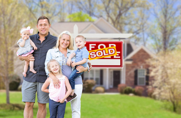feliz joven caucásico familia fuera en frente de su nuevo hogar y vendido real estate sign - Foto, imagen