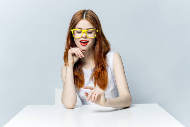 woman in yellow glasses sitting at the table smile emotions desktop - Foto, imagen