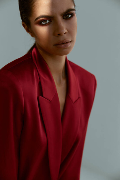 brunette tilalla kätensä pään yläpuolella punainen takki muoti studio koristelu - Valokuva, kuva