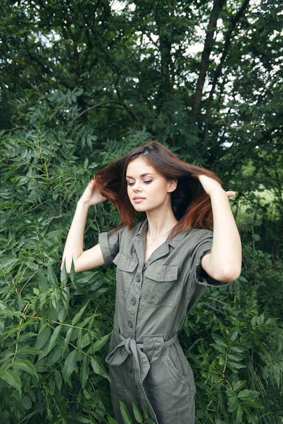 Portrait of a woman touches head hair and landscape green jumpsuit travel  - Photo, Image