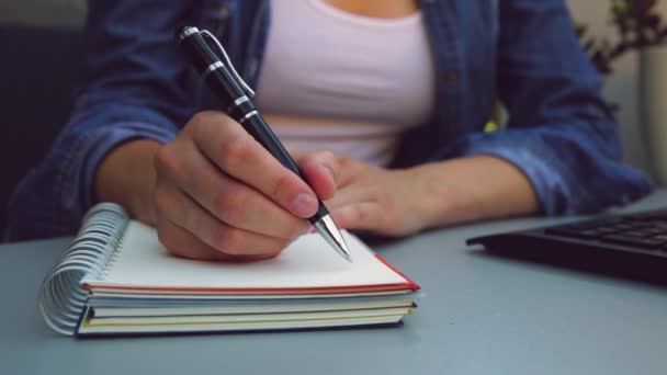 Ręce kobiety z długopisem na notatniku. Nowoczesne, szare biurko. Praca, koncepcja pisania - Materiał filmowy, wideo