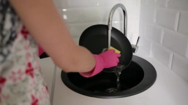 Kobieta myje ręce patelnią pod bieżącą wodą. Młoda gospodyni domowa mycie patelni w zlewie z żółtą gąbką, Ręczne sprzątanie, ręcznie, ręcznie, prace domowe zmywarka - Materiał filmowy, wideo