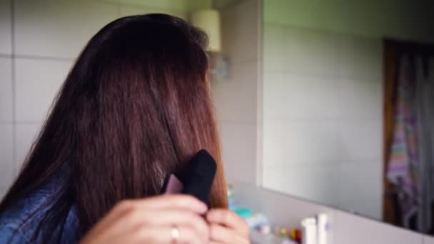 Junge Frau glättet Haare im Badezimmer. Schönheitskonzept - Filmmaterial, Video