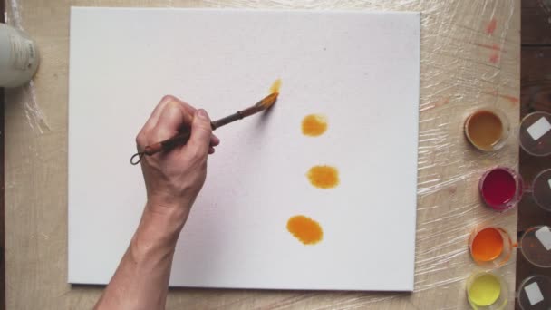 Κάτοψη του αρσενικού καλλιτέχνη ζωγραφίζει Pastel tie dye ή Pastel swirl εικόνα με πορτοκαλί χρώμα σε βρεγμένο καμβά. Ρευστή τέχνη. - Πλάνα, βίντεο