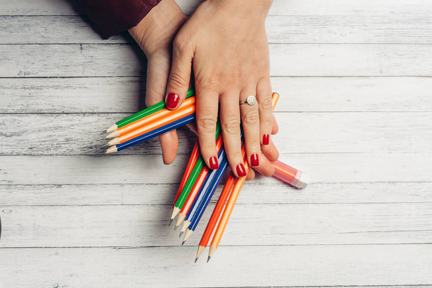 colored pencils in female hands on a wooden background close up - Foto, Imagen