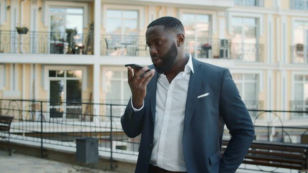 Afro biznesmen rozmawiający na zewnątrz przez telefon komórkowy. Afrykanin stojący blisko biura - Zdjęcie, obraz