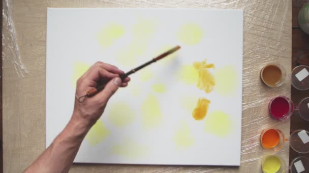 Bovenaanzicht van mannelijke kunstenaar schildert Pastel daskleurstof of Pastel wervelbeeld met gele en bruine verf op nat doek. Vloeibare kunst. - Video