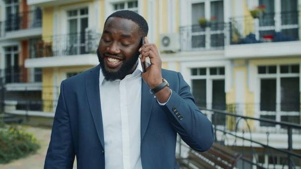 Ενθουσιασμένος Αφρικανός επιχειρηματίας που τηλεφωνεί απ 'έξω. Αφρο άνθρωπος μιλάει smartphone - Φωτογραφία, εικόνα
