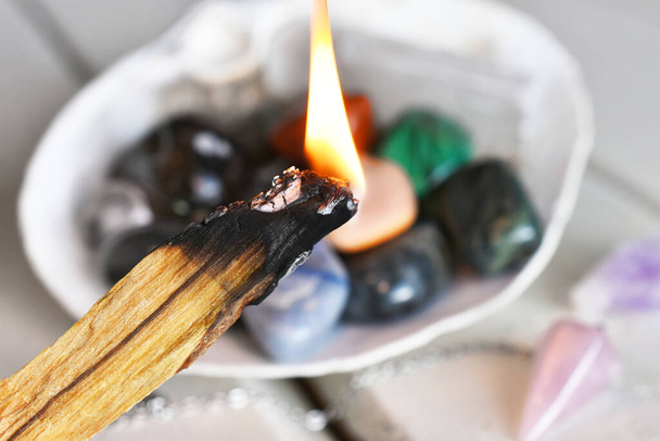 Una imagen de cerca de la quema de madera de acebo con cristales curativos en una concha blanca.  - Foto, Imagen