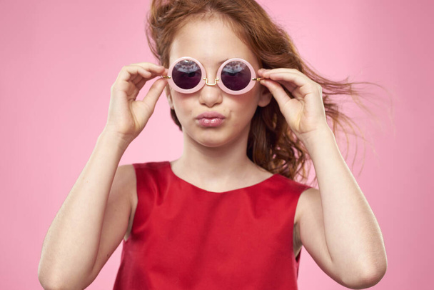 κορίτσι με σγουρά μαλλιά γυαλιά ηλίου παιδική χαρά ροζ φόντο - Φωτογραφία, εικόνα