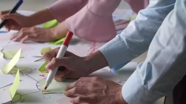 Primo piano di due colleghi d'affari appoggiati alla scrivania che prendono appunti sugli adesivi con pennarelli - Filmati, video