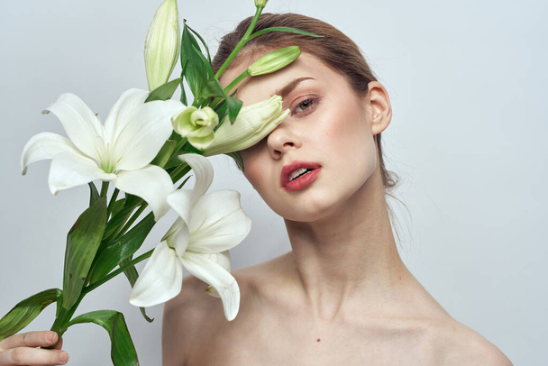 femme avec des fleurs blanches sur fond gris portrait gros plan mode maquillage - Photo, image