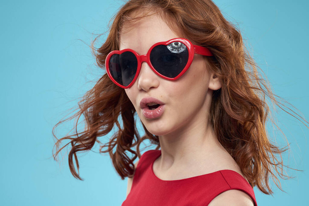 chica con gafas de sol de pelo rizado vestido rojo y la infancia divertido fondo azul - Foto, Imagen