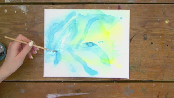 Sıvı Sanat. Soyut mavi ve sarı resim. Kadın ressamın üst görünüşü, ıslak tuvale soyut pembe şekiller çizer. - Video, Çekim