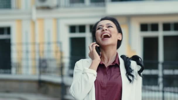 Emocionální smíšená závodnice, která se venku směje při telefonátu. žena mluví mobilně - Záběry, video