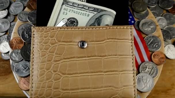 Otwarty portfel, z którego wystaje kilkaset amerykańskich dolarów i wiele rozrzuconych amerykańskich centów obraca się w kółko. Amerykańska flaga widziana spod torebki. Zbliżenie. - Materiał filmowy, wideo