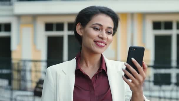Smiling mixed race woman video chatting outside. Lady looking phone screen - Footage, Video