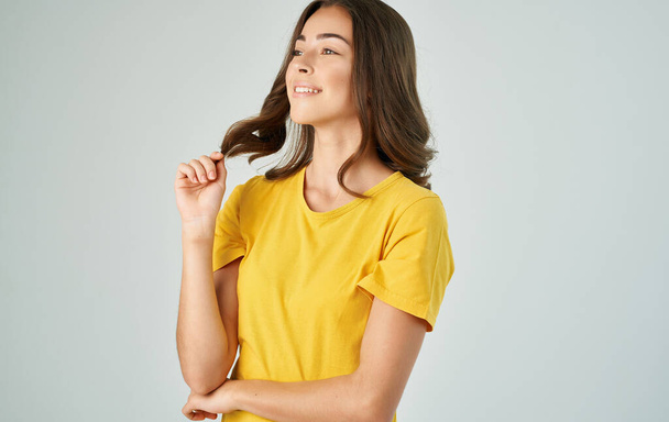ładna brunetka w żółtym t-shirt szary tło uśmiech emocje - Zdjęcie, obraz