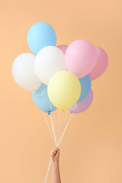 Рука людини з повітряними кульками на кольоровому фоні
 - Фото, зображення