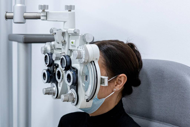 Young patient eye examination at optometrist using phoropter - Photo, Image