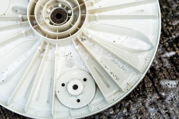La placa base del tambor de la lavadora se ensucia en un piso de cemento, eliminado para la limpieza. - Foto, Imagen