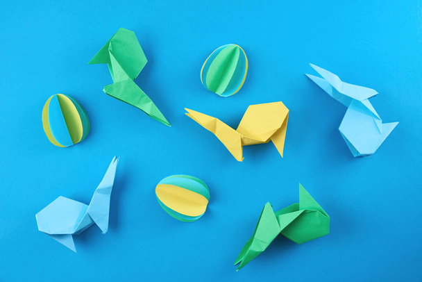 Papel origami Esater conejos y huevos de colores sobre fondo azul. Concepto de celebración Pascua - Foto, Imagen