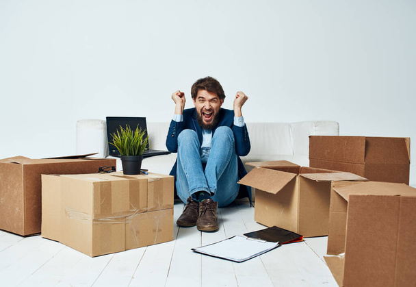 Hombre sentado en el suelo con cajas de cosas que se mueven a la oficina desempacando estilo de vida - Foto, Imagen