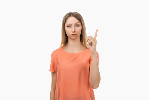 Retrato de uma jovem loira séria que mostra o dedo indicador, repreendendo ou repreendendo alguém. A rapariga levanta o dedo e diz: Estúdio tiro, fundo branco - Foto, Imagem