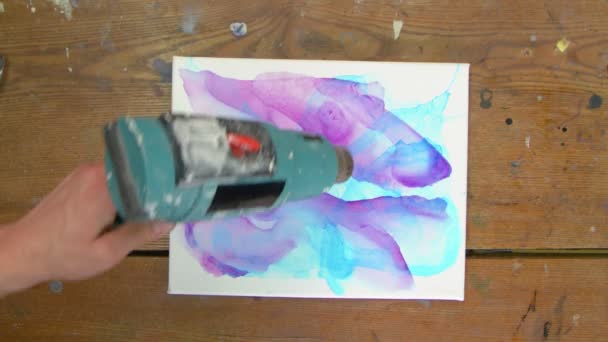 Fluido Art. Pittura astratta blu. Vista dall'alto dell'artista femminile utilizza asciugatrice per asciugare il suo nuovo quadro astratto con i colori blu e viola - Filmati, video