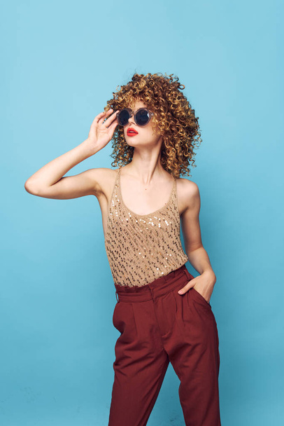 Csinos nő göndör haj napszemüveg divat ruhák piros nadrág  - Fotó, kép