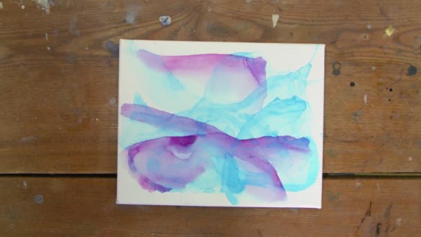 流体芸術。抽象的な青の絵画。女性アーティストのトップビューは、青と紫の色で彼女の新しいフルードアート画像を乾燥させるために乾燥機を使用します - 映像、動画
