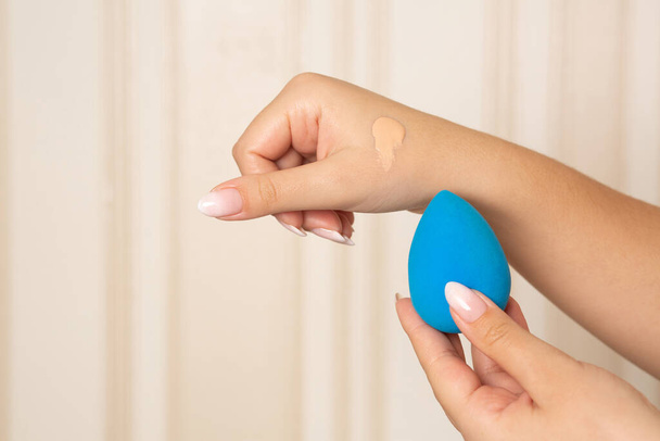 Artista de maquillaje aplicando base líquida con licuadora de belleza azul de su mano. Espacio para texto - Foto, Imagen