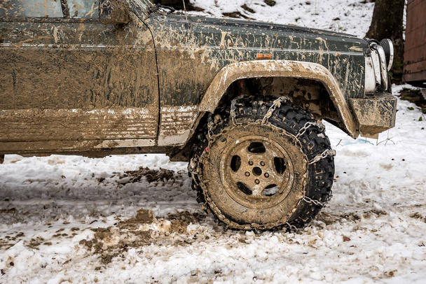 chain on wheel of dirty car in snowy winter - Foto, Bild