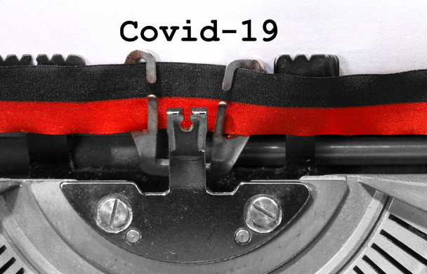 Covid-19 napisany starą maszyną do pisania na białym arkuszu - Zdjęcie, obraz