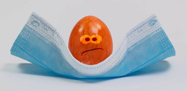 Uovo di Pasqua colorato su una maschera di faccia medica - Foto, immagini